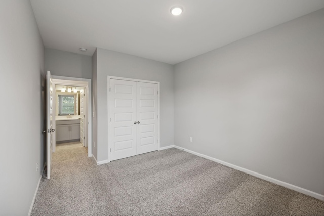 unfurnished bedroom featuring a closet, baseboards, and light colored carpet