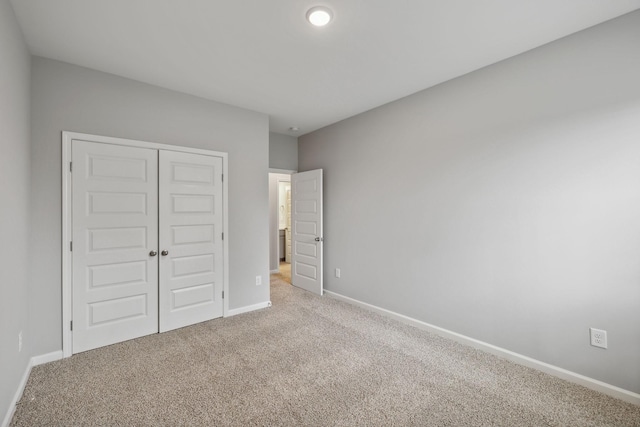 unfurnished bedroom with a closet and light colored carpet