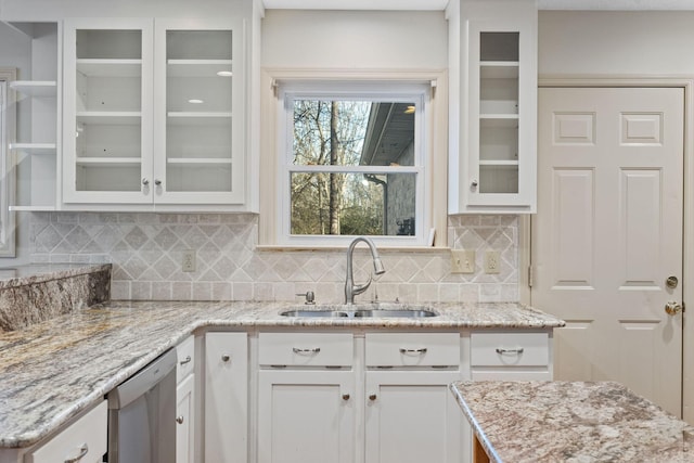 kitchen with sink, white cabinets, stainless steel dishwasher, and light stone countertops