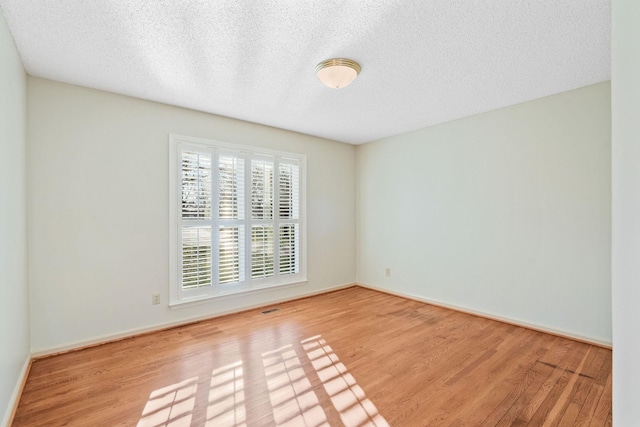 unfurnished room with a textured ceiling and light hardwood / wood-style flooring