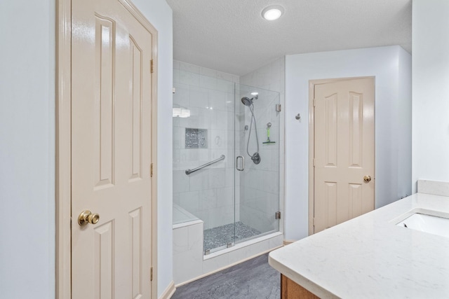 bathroom featuring a textured ceiling, a shower with door, and vanity