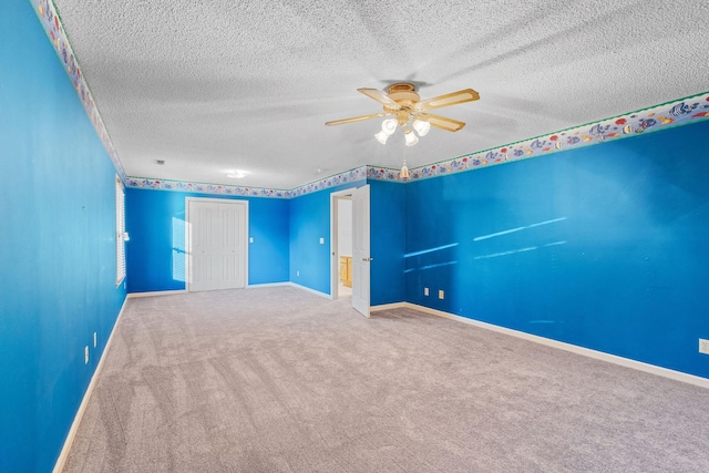 carpeted empty room featuring ceiling fan and a textured ceiling