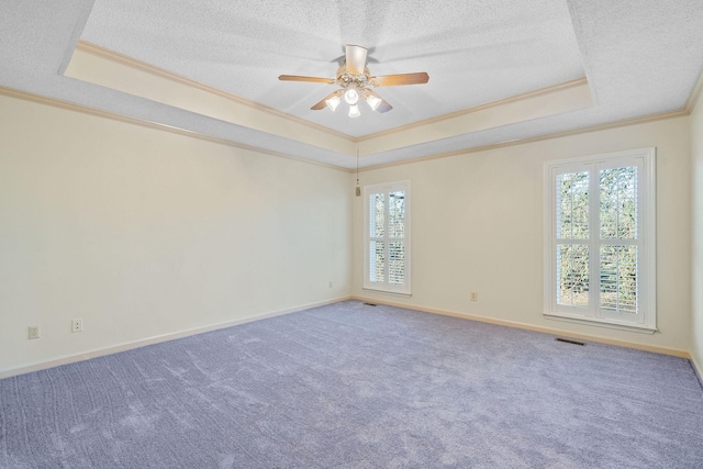 carpeted spare room featuring ceiling fan, a textured ceiling, a tray ceiling, and ornamental molding