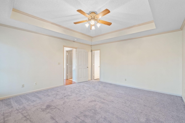 spare room featuring carpet floors, a textured ceiling, a tray ceiling, and ornamental molding