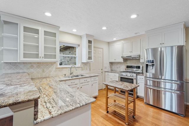 kitchen with light hardwood / wood-style flooring, sink, white cabinets, light stone countertops, and stainless steel appliances