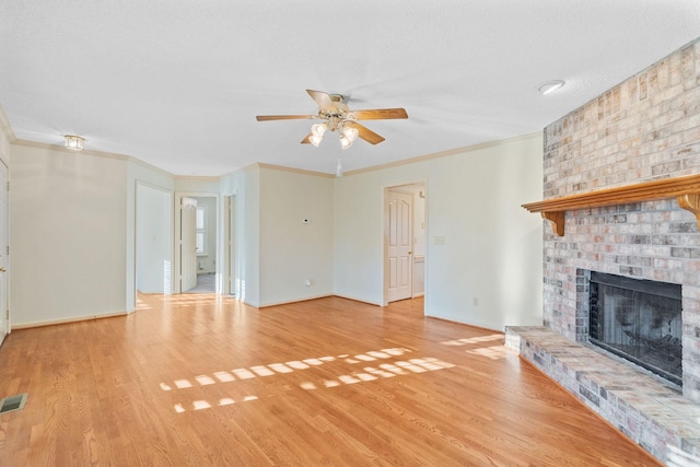 unfurnished living room featuring light wood-type flooring, ceiling fan, crown molding, and a fireplace