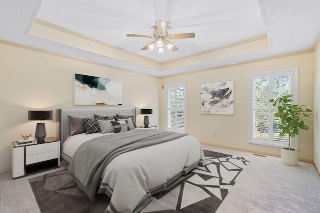 carpeted bedroom featuring ceiling fan, multiple windows, ornamental molding, and a raised ceiling