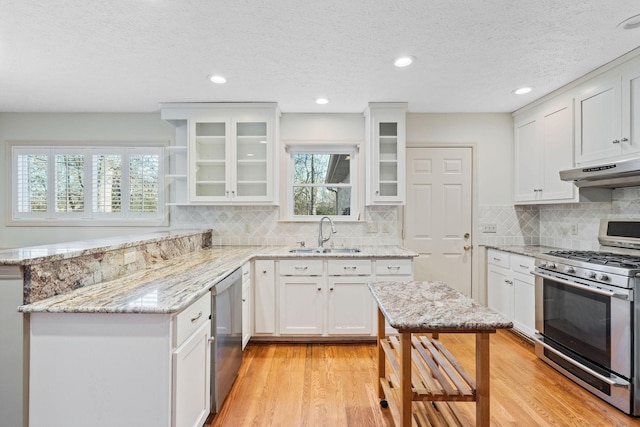 kitchen featuring appliances with stainless steel finishes, sink, white cabinets, light stone counters, and plenty of natural light