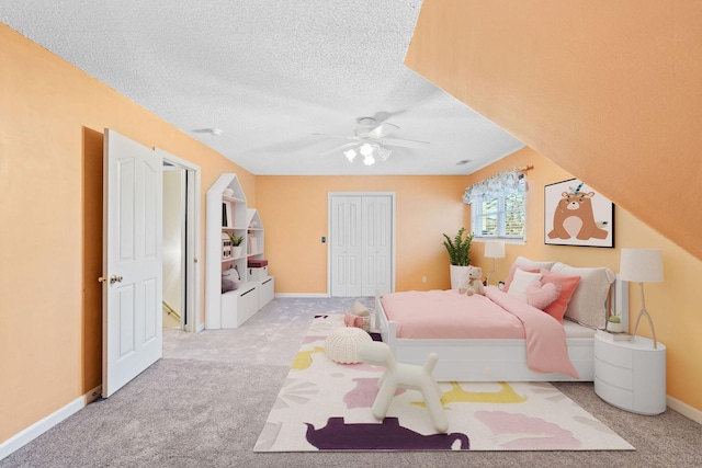 bedroom featuring ceiling fan, light colored carpet, a textured ceiling, and a closet