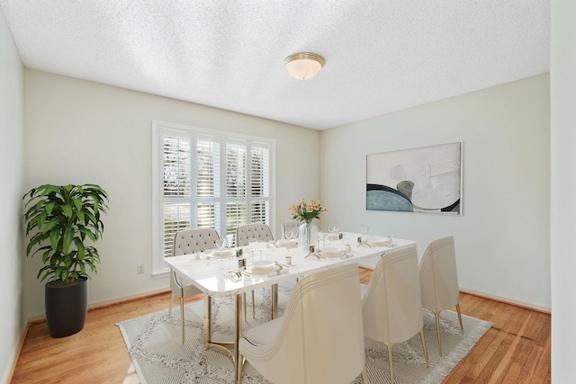 dining room with light wood-type flooring and a textured ceiling