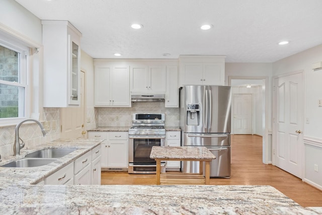 kitchen with light hardwood / wood-style flooring, appliances with stainless steel finishes, sink, tasteful backsplash, and white cabinetry