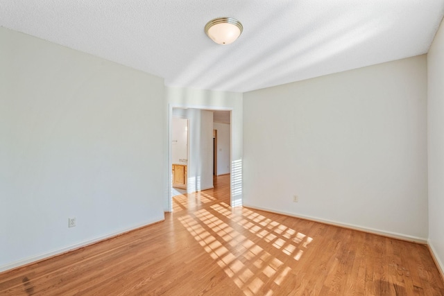 empty room with light hardwood / wood-style floors and a textured ceiling