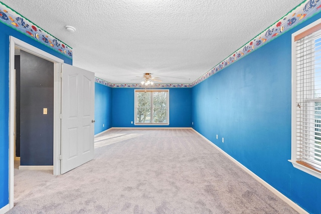 carpeted spare room with ceiling fan and a textured ceiling