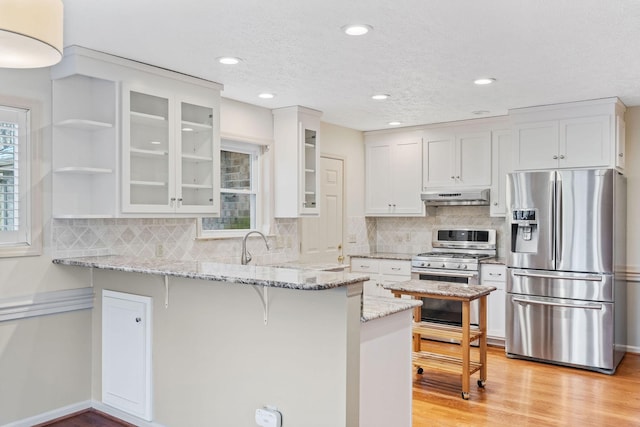 kitchen featuring light stone counters, white cabinets, appliances with stainless steel finishes, and kitchen peninsula