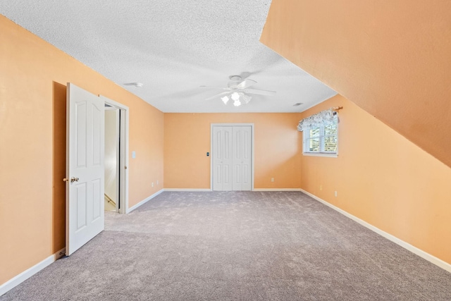 interior space featuring a textured ceiling, light colored carpet, and ceiling fan