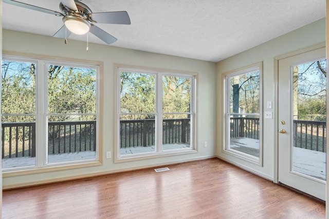 unfurnished sunroom with ceiling fan and plenty of natural light