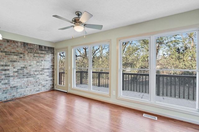 unfurnished sunroom with ceiling fan