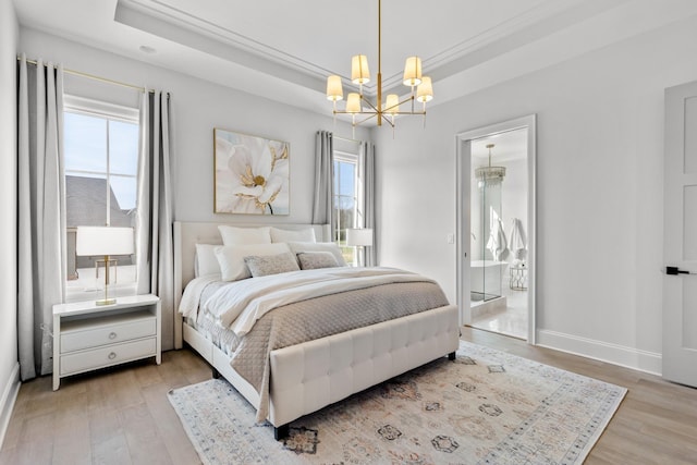 bedroom with a raised ceiling, a chandelier, and light wood-type flooring