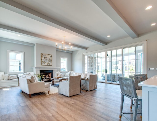 living room with light hardwood / wood-style floors, a chandelier, and beamed ceiling