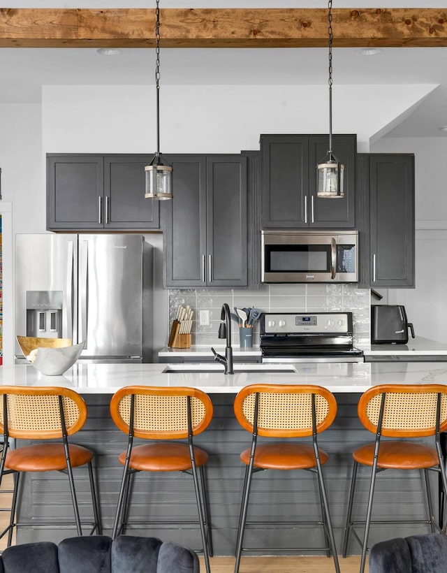 kitchen with stainless steel appliances, hanging light fixtures, tasteful backsplash, and a breakfast bar