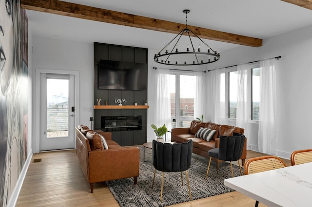 living room featuring light hardwood / wood-style floors, a large fireplace, beam ceiling, and a healthy amount of sunlight