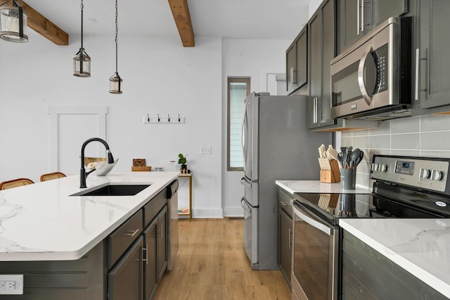 kitchen with appliances with stainless steel finishes, beamed ceiling, tasteful backsplash, sink, and hanging light fixtures