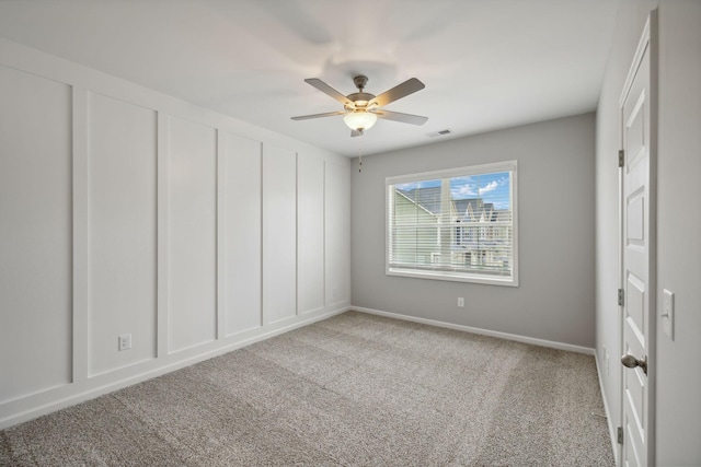 unfurnished bedroom featuring visible vents, a decorative wall, ceiling fan, and carpet floors