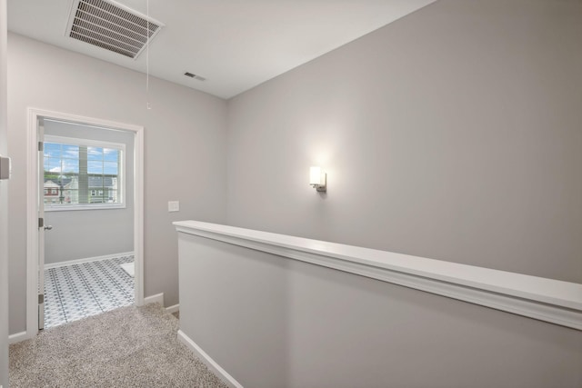 hallway featuring attic access, baseboards, visible vents, and carpet floors