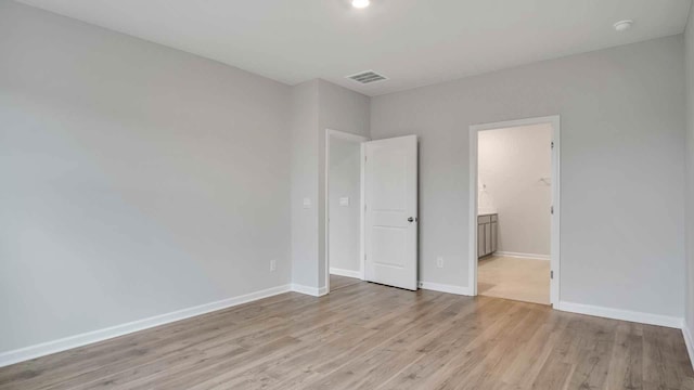 unfurnished bedroom with light wood-type flooring and ensuite bathroom