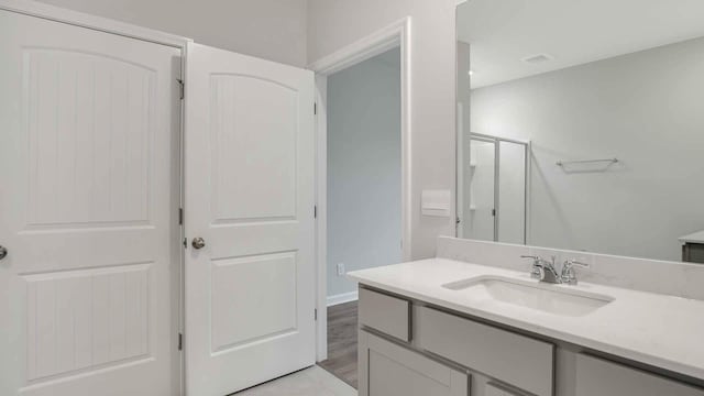 bathroom featuring a shower with shower door and vanity