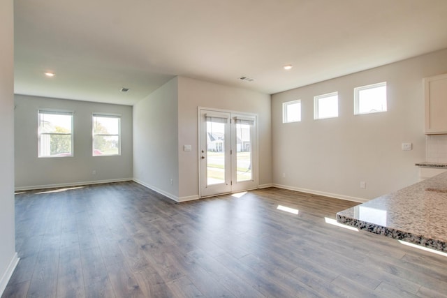 interior space with backsplash, hardwood / wood-style flooring, and light stone counters