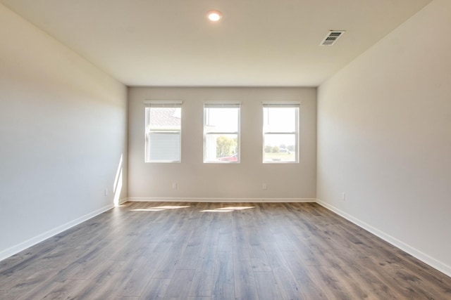 spare room featuring a healthy amount of sunlight and dark hardwood / wood-style floors