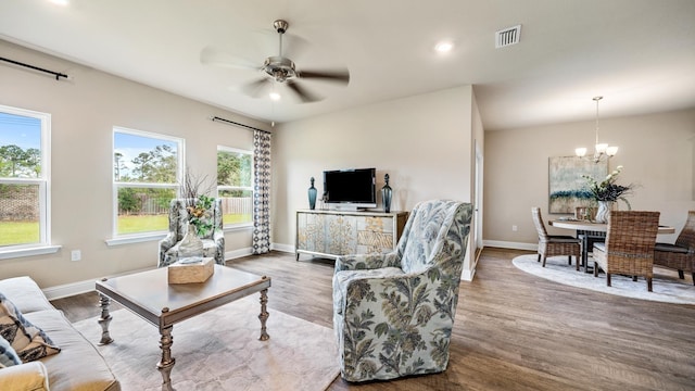 living room featuring ceiling fan with notable chandelier and wood-type flooring