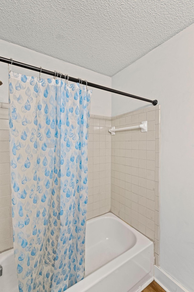 bathroom featuring shower / bath combo with shower curtain and a textured ceiling