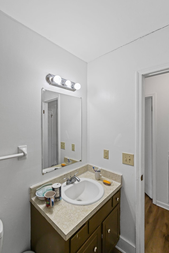 bathroom with hardwood / wood-style floors, toilet, and vanity