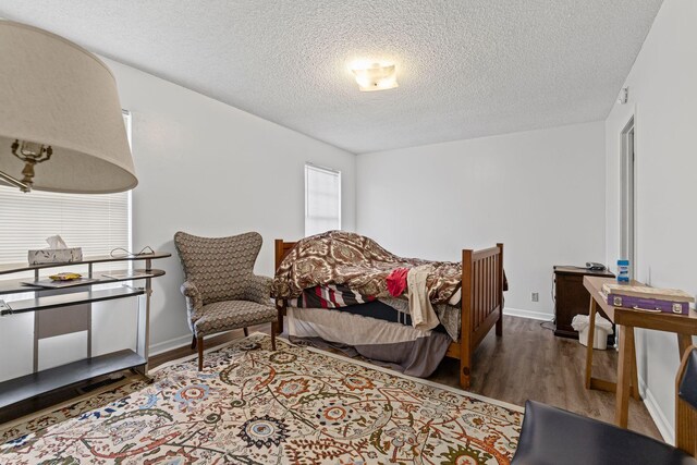 bedroom with a textured ceiling and wood-type flooring