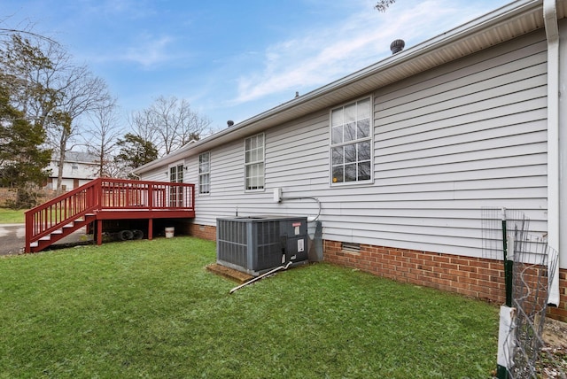 view of side of home featuring a wooden deck, central AC, and a yard