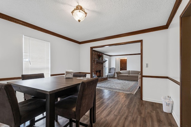 dining space with crown molding, a textured ceiling, a brick fireplace, and dark hardwood / wood-style flooring