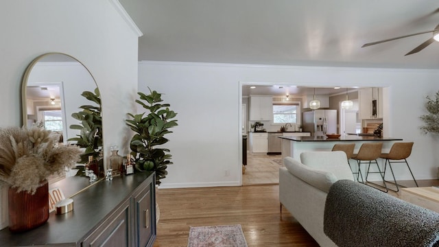 interior space with ceiling fan, crown molding, and light hardwood / wood-style floors