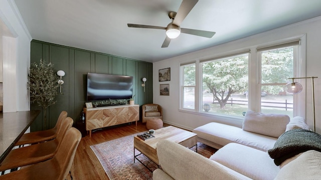 living room with wood-type flooring, plenty of natural light, ceiling fan, and crown molding