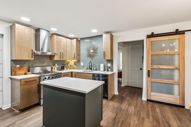 kitchen featuring wall chimney exhaust hood, stainless steel range with gas cooktop, a barn door, black dishwasher, and a kitchen island