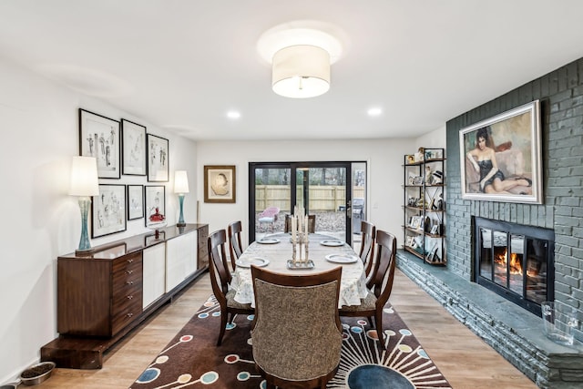 dining room featuring a brick fireplace and light hardwood / wood-style floors