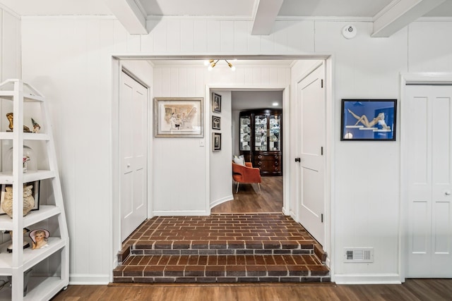 hall with ornamental molding and beam ceiling