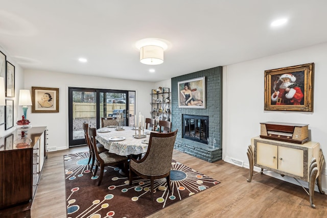 dining room with a brick fireplace and light hardwood / wood-style flooring