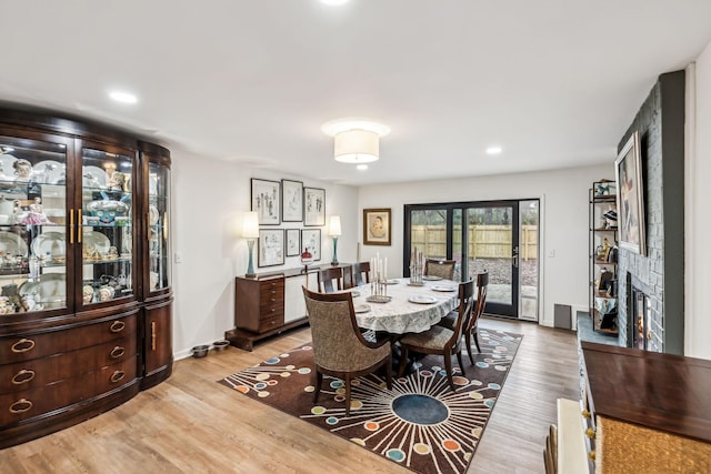 dining space with light wood-type flooring and a stone fireplace