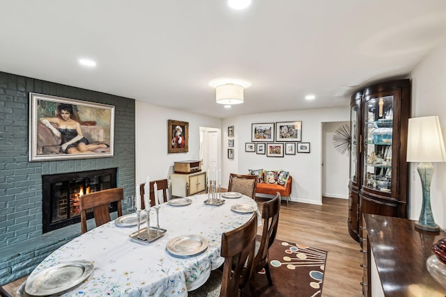 dining space with a brick fireplace and light hardwood / wood-style floors