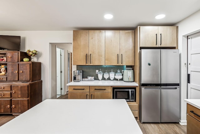 kitchen with stainless steel appliances, light hardwood / wood-style floors, and tasteful backsplash