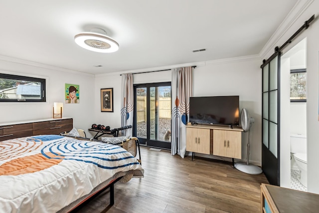 bedroom featuring ornamental molding, multiple windows, dark hardwood / wood-style flooring, and a barn door