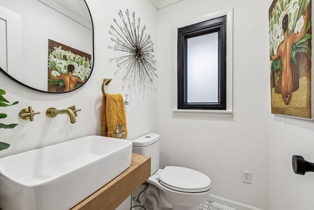 bathroom with sink, toilet, and ornamental molding