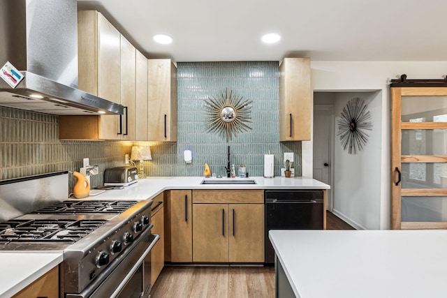 kitchen featuring black dishwasher, tasteful backsplash, stainless steel stove, wall chimney range hood, and sink